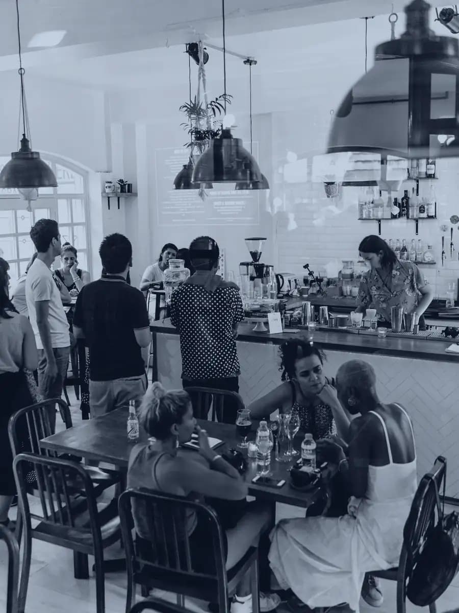 A busy cafe with customers at the counter and full tables